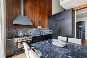 A modern kitchen with a marble countertop, stainless steel appliances, and wooden cabinetry.
