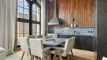 A modern kitchen with a dining table and chairs, wooden cabinets, and a large window.