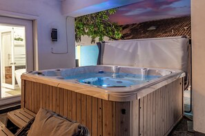 A hot tub with wooden panels, a bench, and a view of a garden through a window. - Elite Luxury Pickleball Palace-Heated Pool (Scottsdale)