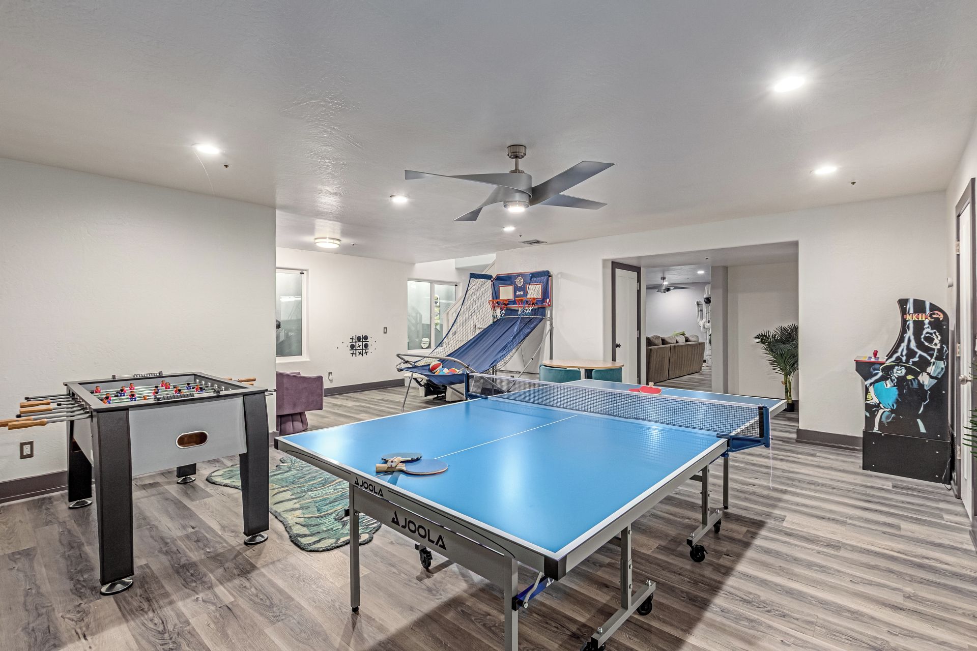A room with a foosball table, ping pong table, and a slide.