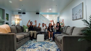 A living room with a sofa, a coffee table, and a staircase in the background. - Elite Luxury Pickleball Palace-Heated Pool (Scottsdale)
