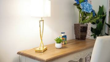 Ein Holznachttisch mit einer Lampe, einer kleinen Topfpflanze und einem dekorativen Behälter.