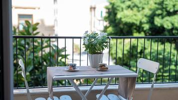 Ein Balkon mit Tisch, Stühlen, einer Topfpflanze und einer Tasse mit Untertasse.