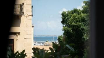 A view of a building with a balcony, a clear sky, and a distant view of a body of water with a bridge.