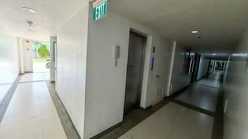 A hotel corridor with an exit sign, a phone, and a door.