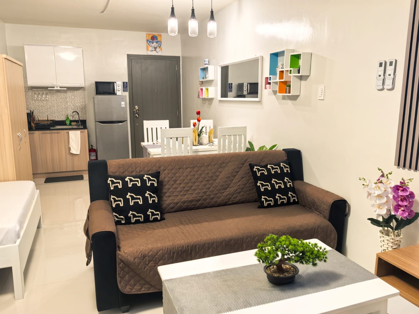 A modern living room with a brown sofa, a white coffee table, and a small potted plant.