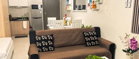 Una sala de estar moderna con un sofá marrón, una mesa de centro blanca y una pequeña planta en maceta.