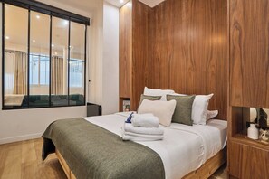 Ein modernes Schlafzimmer mit einem großen Bett, Holzwandverkleidung, einem großen Fenster mit Vorhängen und Blick auf einen Balkon.