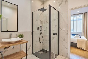 Ein modernes Badezimmer mit einer Duschkabine aus Glas, einem Holzwaschtisch und einem großen Spiegel.