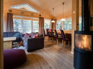 A cozy cabin interior with a sofa, dining table, chairs, and a wood-burning stove. - Cabin in Turrach With Sauna and Balcony (Stadl-Predlitz)