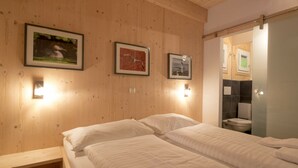 Quarto com duas camas, paredes de madeira e quadros emoldurados.