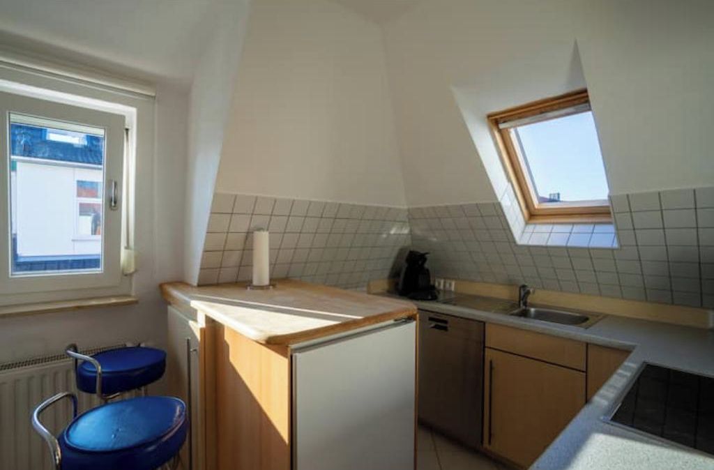 Eine kleine Küche mit Fenster, Spüle und Kühlschrank.