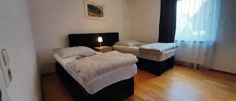A room with two beds, a nightstand, a lamp, and a painting on the wall.