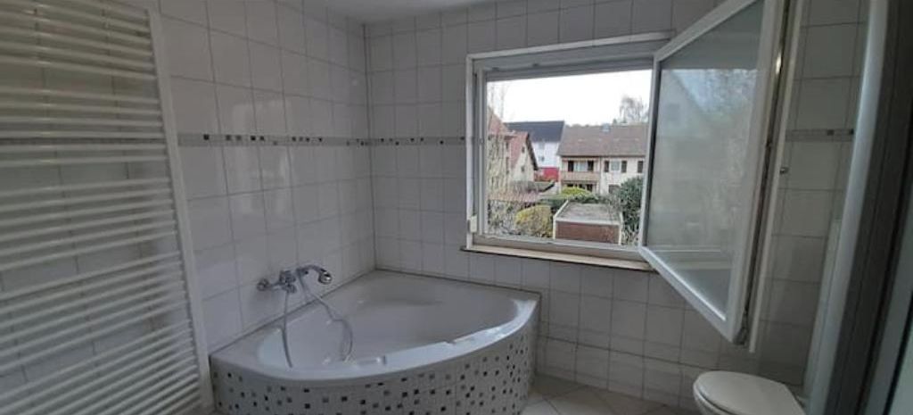 Ein Badezimmer mit Badewanne, Toilette und einem Fenster.
