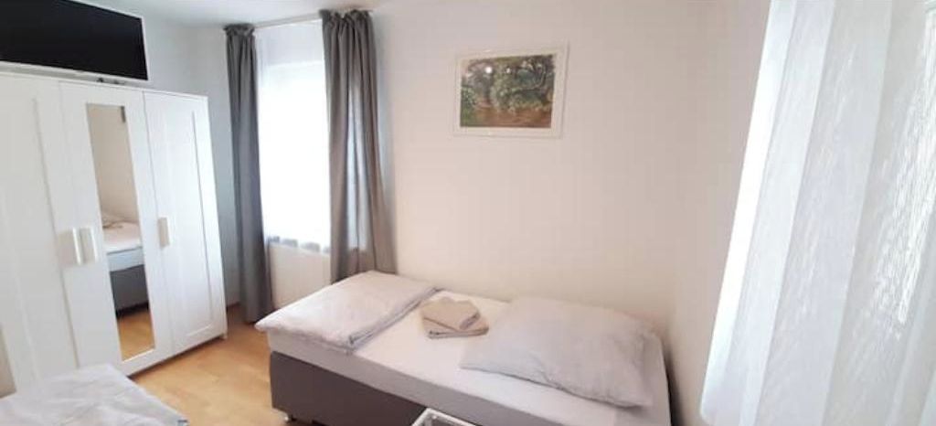 Un dormitori amb un llit, un armari i un quadre a la paret.
