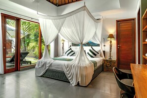 Ein Schlafzimmer mit Himmelbett, Holzboden, Esstisch und Blick auf Grünfläche.