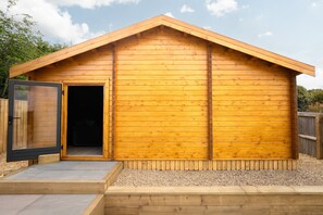 A wooden shed with a sloped roof, a door, and a small step leading up to it. - St Andrews Golf House | Private Sim & Cinema (St Andrews)