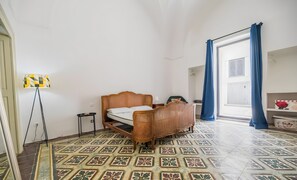 A room with a bed, a floor lamp, and a patterned floor.