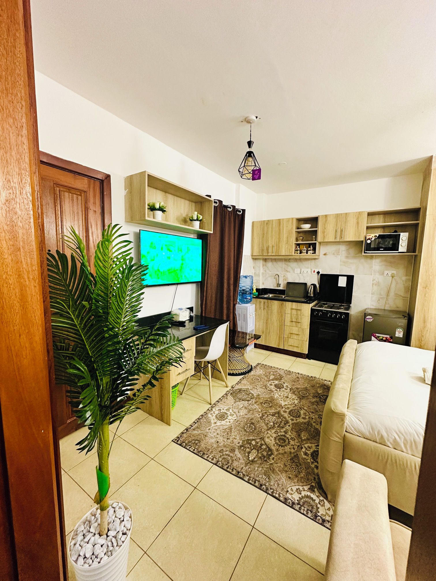 Un espacio habitable compacto con kitchenette, comedor y televisor.