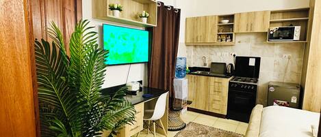 Un espacio habitable compacto con kitchenette, comedor y televisor.