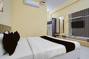 A hotel room with a bed, a flat-screen TV, a mirror, and a minibar. - Hote O Iiit Square Bhubaneswar (Bhubaneshwar)