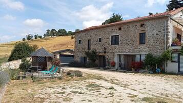 A stone building with a tiled roof, a covered outdoor seating area, and a paved driveway.