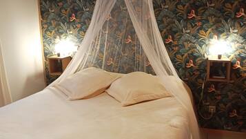 Ein Bett mit Baldachin, zwei Nachttische mit Lampen und blumiger Tapete.