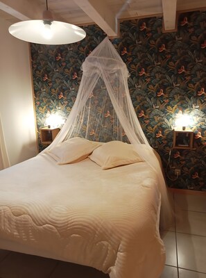 A bed with a canopy, two bedside lamps, and a floral wallpaper.