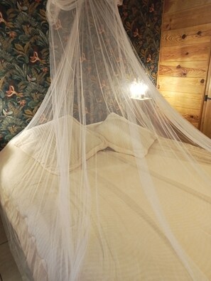Un letto a baldacchino, un armadio in legno e una carta da parati con motivi floreali.