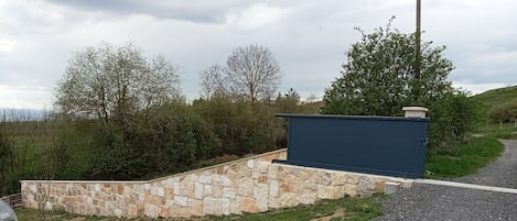 Un mur de pierre avec une structure bleue, un chemin de gravier et de la verdure.