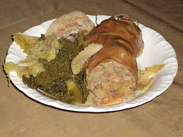 Un plato con un rollo de carne, verduras y salsa.