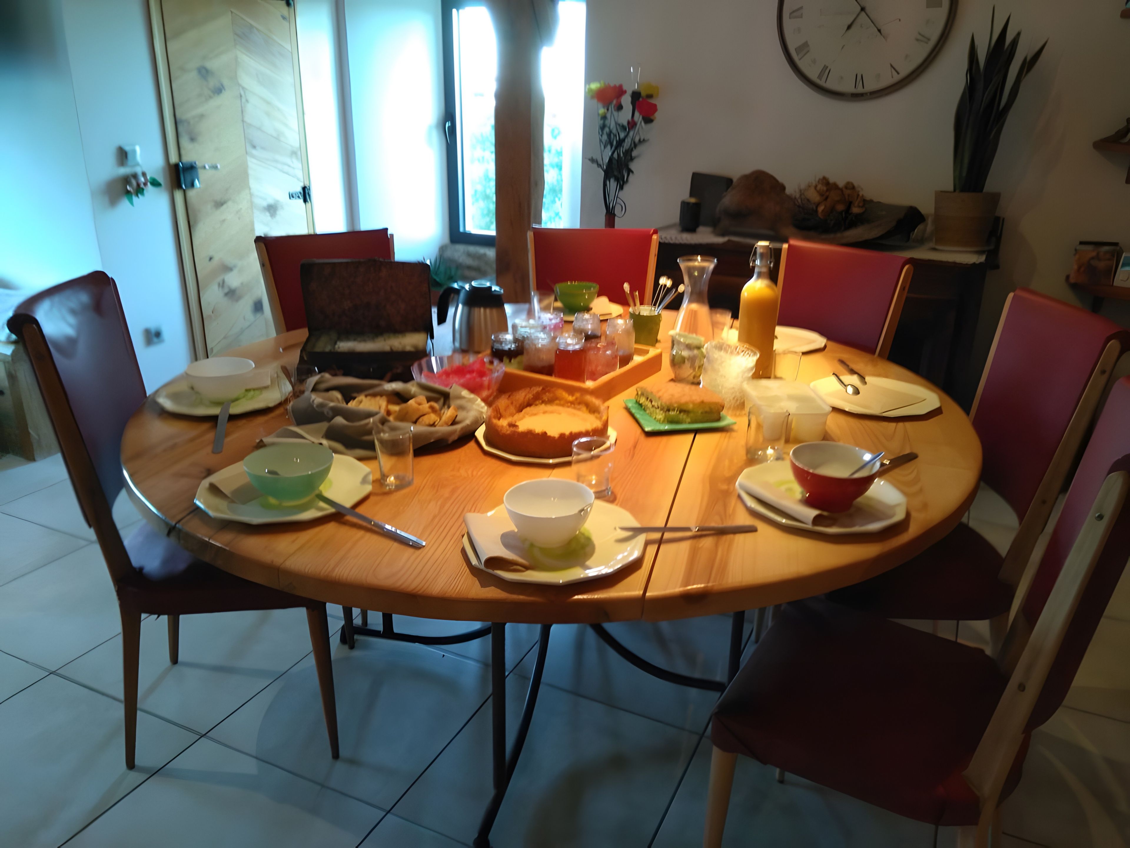 A dining table set with various dishes, glasses, and utensils, surrounded by chairs.