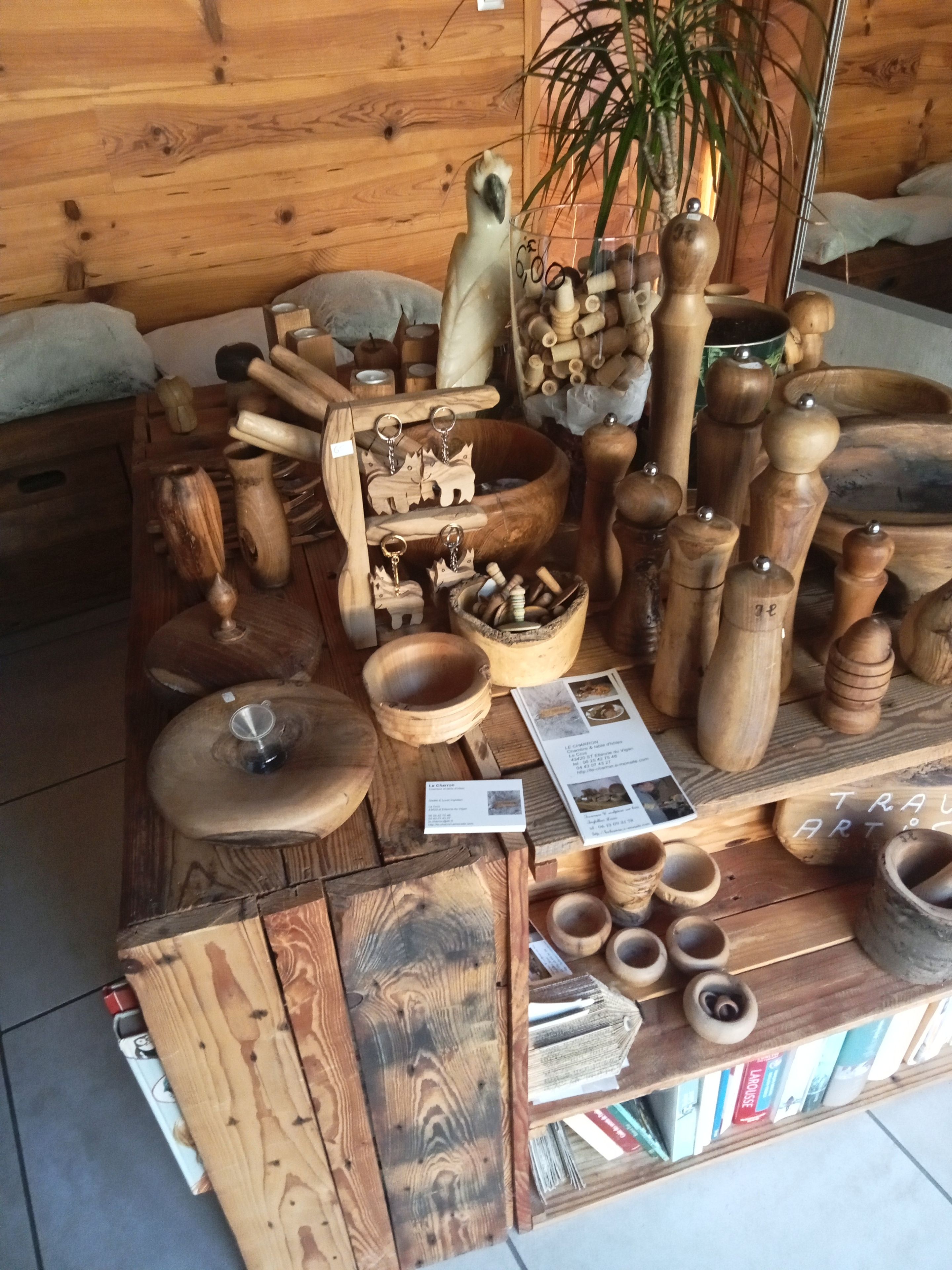Ein Holzboden präsentiert verschiedene geschnitzte Holzprodukte, darunter Schüsseln und Behälter, die auf Regalen und Tischen angeordnet sind.