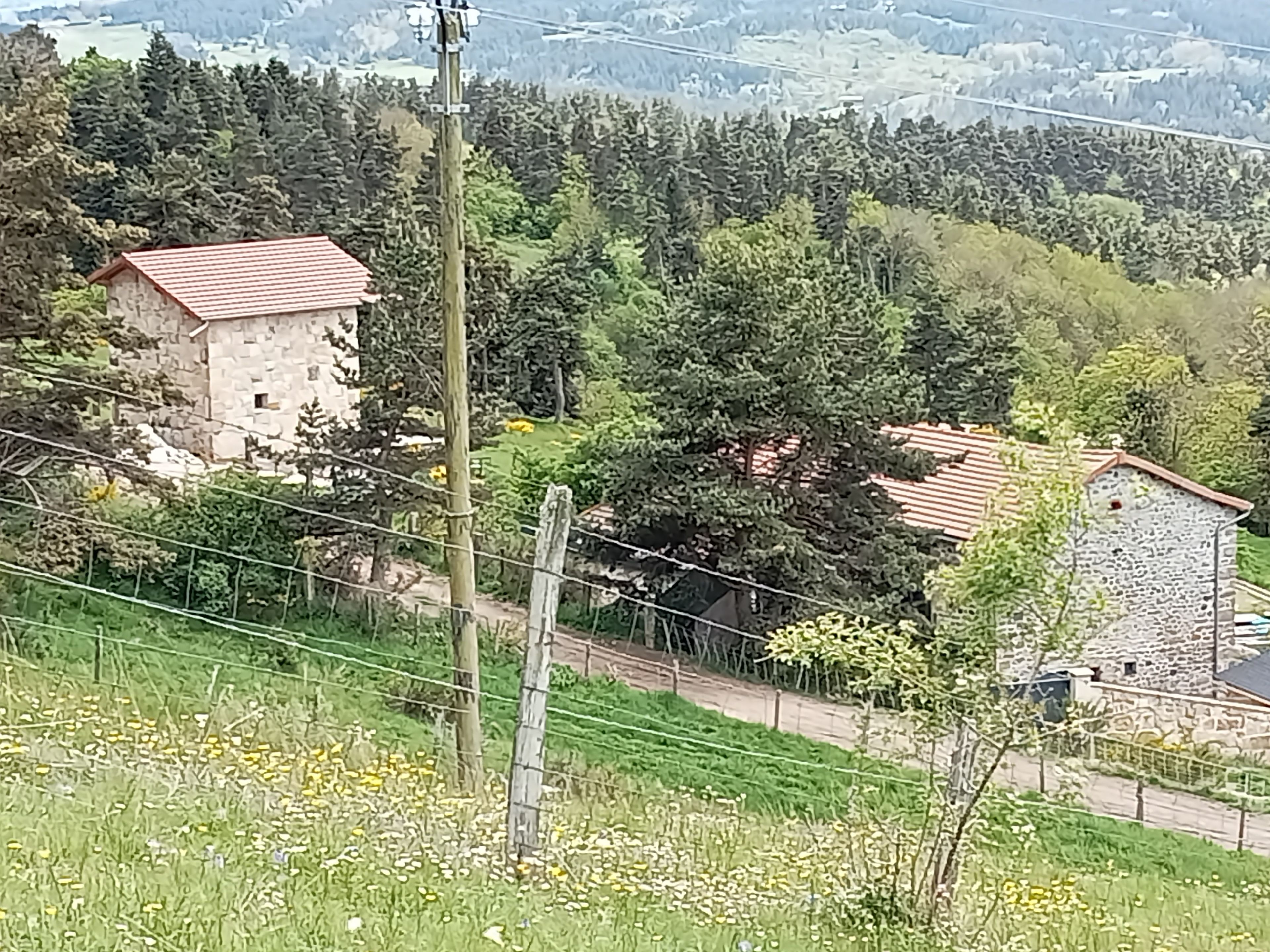 Un paysage rural avec des bâtiments en pierre, une route et une clôture.