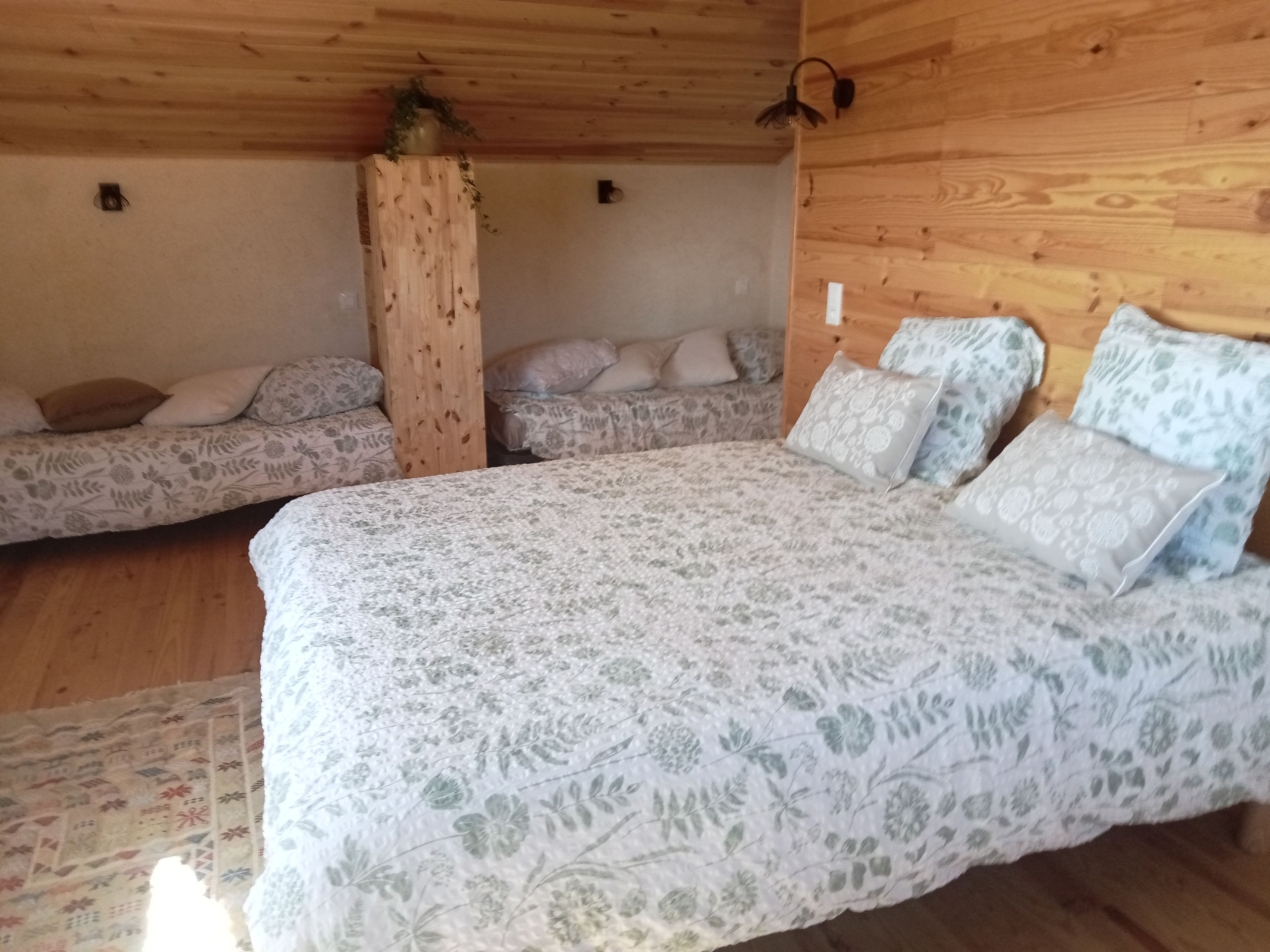 Een houten hutje met een bed, twee banken en een houten zuil.