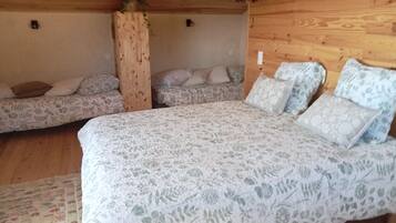 Een houten hutje met een bed, twee banken en een houten zuil.