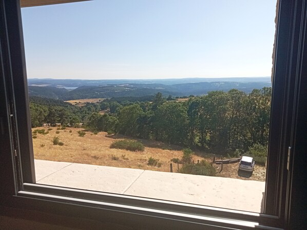 A window view of a landscape with a road and a vehicle.