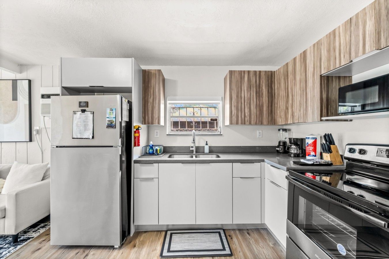 A modern kitchen with white cabinets, stainless steel appliances, and a wooden accent wall.