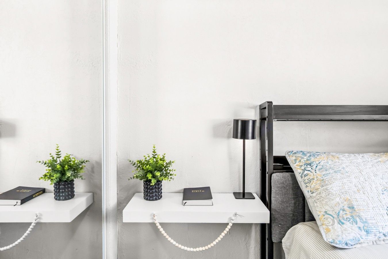 A modern bedroom with a bed, bedside tables, a lamp, and decorative pillows.