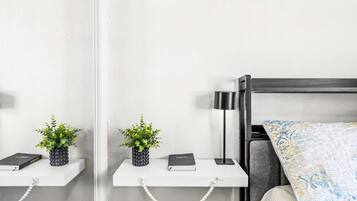 A modern bedroom with a bed, bedside tables, a lamp, and decorative pillows.