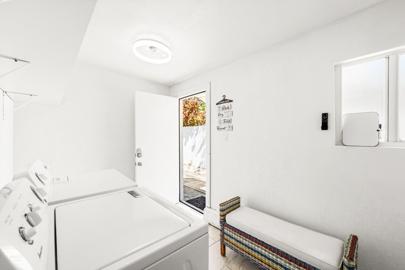 A laundry room with a washing machine, dryer, and a bench.
