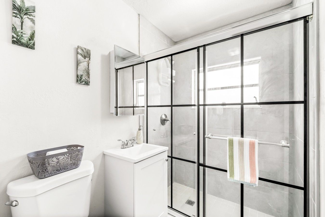 A modern bathroom with a glass shower enclosure, a white sink, and a toilet.