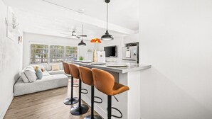 Een moderne keuken met een bar, een grijze bank en een groot raam.