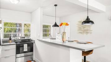 A modern kitchen with a central island, stainless steel appliances, and pendant lighting.