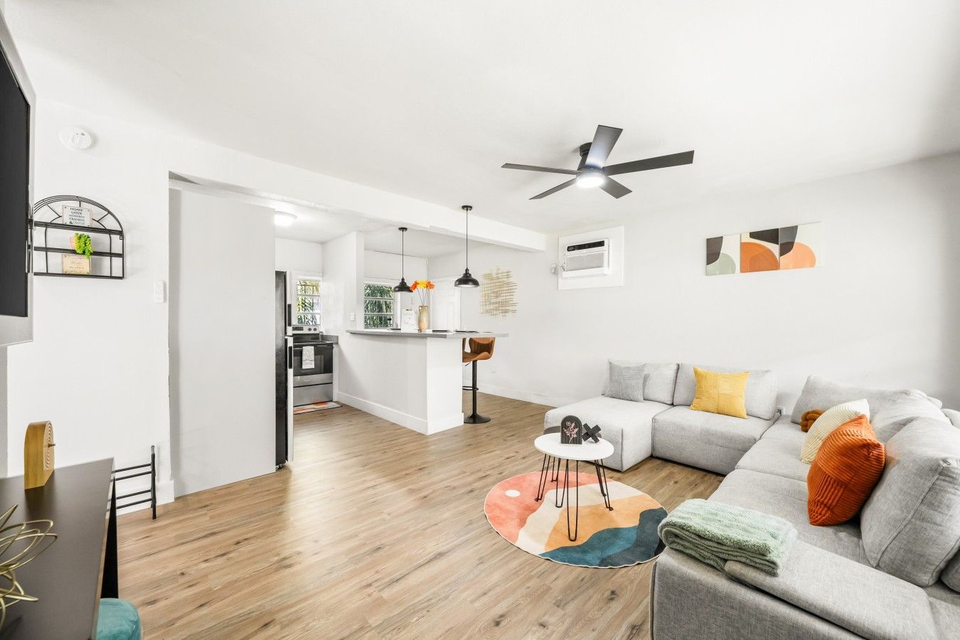 A modern living room with a grey sofa, a coffee table, and a ceiling fan.