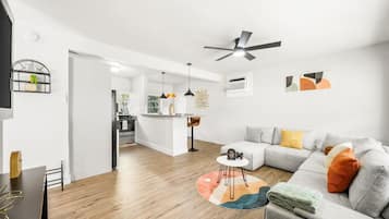 A modern living room with a grey sofa, a coffee table, and a ceiling fan.