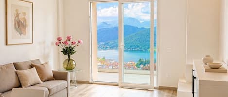 Un salon moderne comprenant un canapé, une table à manger et offrant une vue sur un paysage montagneux grâce à de grandes portes vitrées.