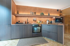 Eine moderne Küche mit grauen Schränken, einem eingebauten Backofen und einer Mikrowelle.