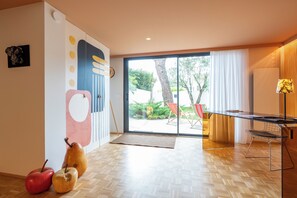 Ein modernes Interieur mit Holzboden im Fischgrätmuster, einer Glastür, die zu einem Außenbereich führt, und einem Esstisch mit Stühlen.
