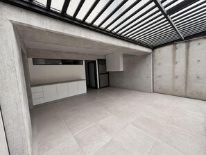Ein geräumiger Raum mit hoher Decke, einer Betonwand und einer geneigten Dachkonstruktion.